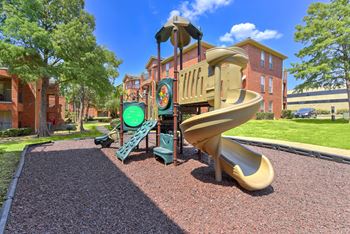 A playground with a slide and a green and yellow play structure.